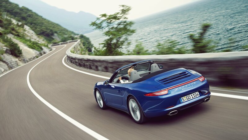 Blue Porsche convertible on coastal road