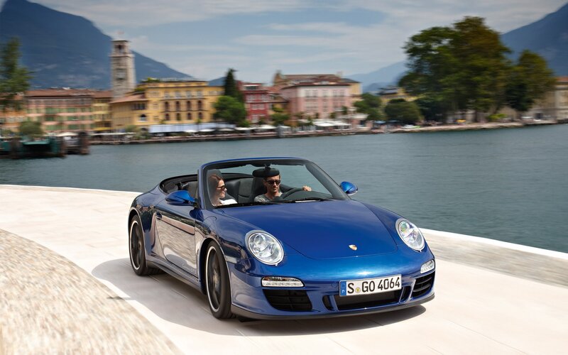 Blue Porsche convertible on lakeside road