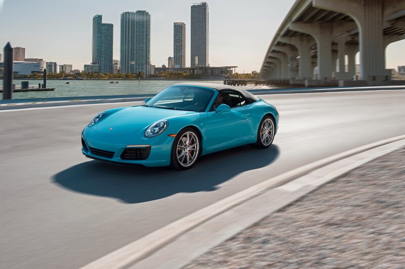 Blue Porsche driving on a city road