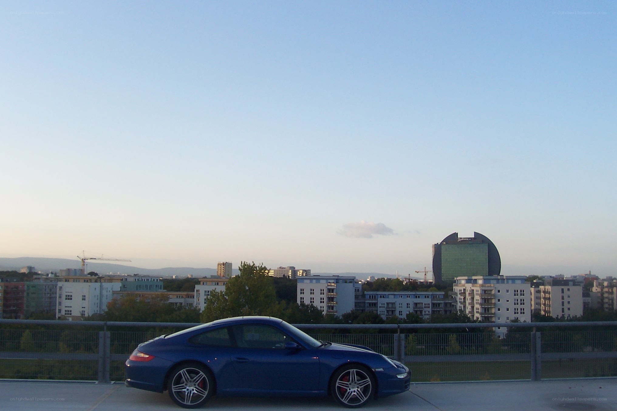 Blue Porsche on a city bridge