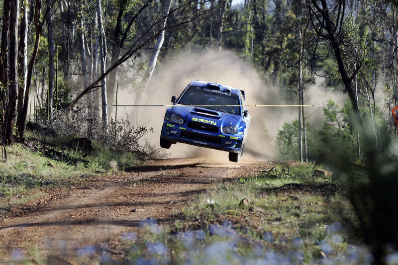 Blue rally car in mid-air jump