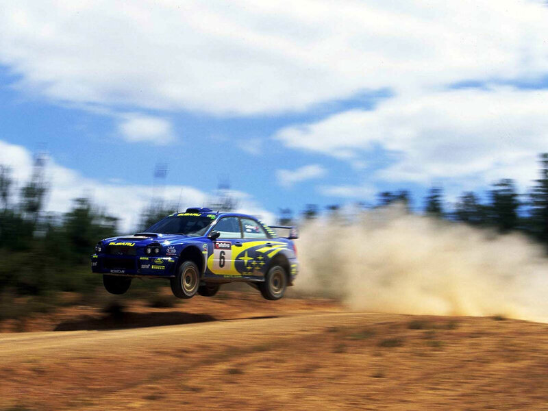 Blue rally car in mid-air jump