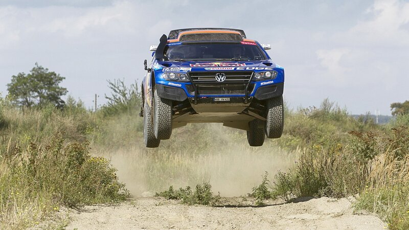 Blue rally car in mid-air jump