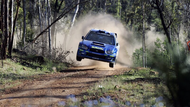 Blue rally car in mid-air jump