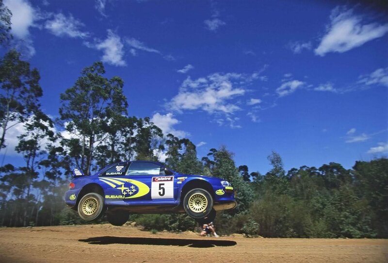 Blue rally car in mid-air jump