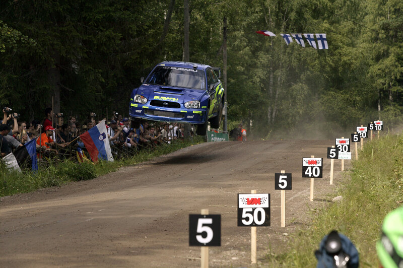 Blue rally car in mid-air jump