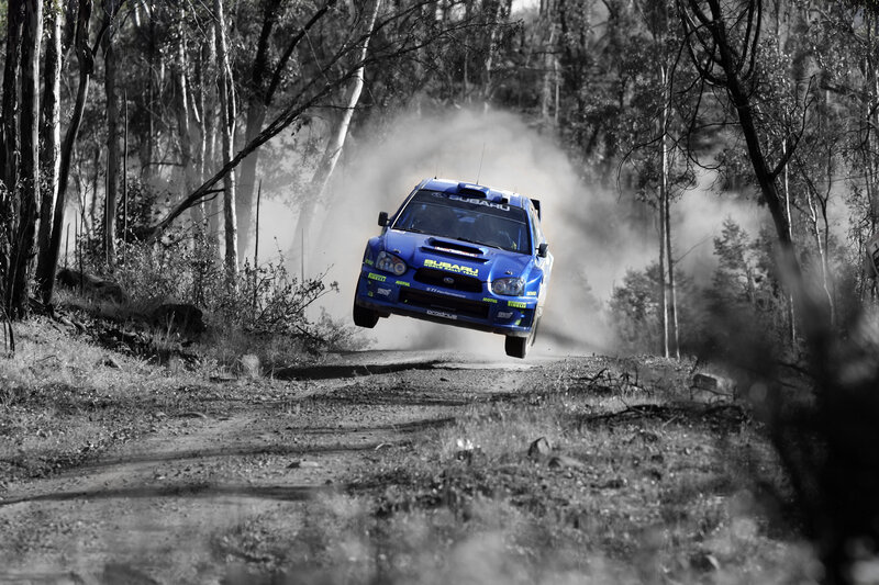 Blue rally car in mid-air jump