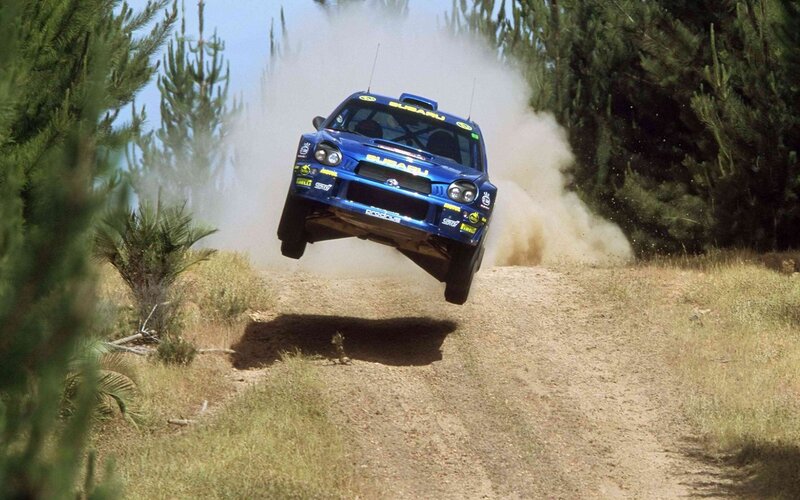 Blue rally car in mid-air jump