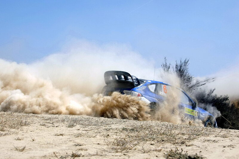 Blue rally car kicking up dust