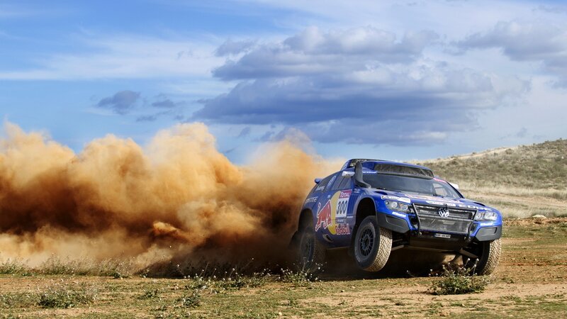 Blue rally car kicking up dust
