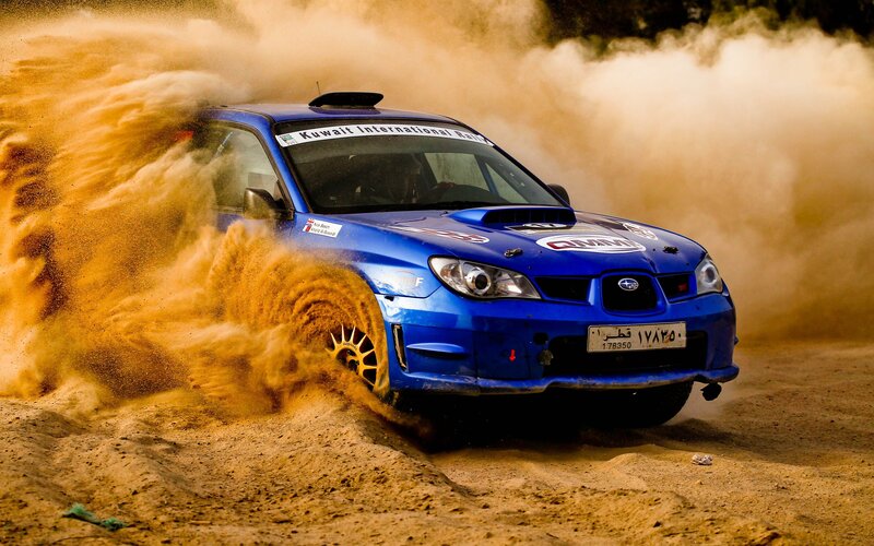 Blue rally car kicking up dust
