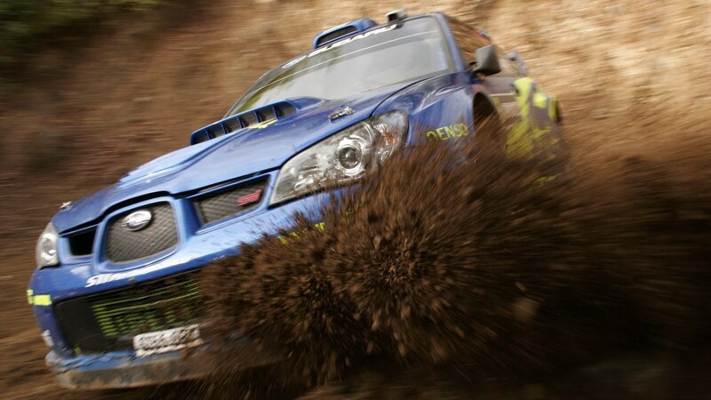 Blue rally car kicking up mud