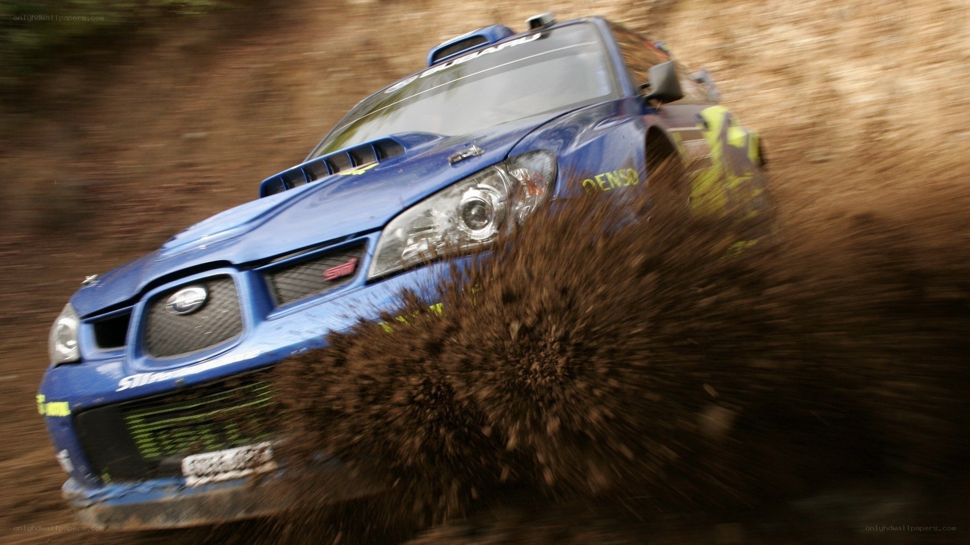 Blue rally car kicking up mud