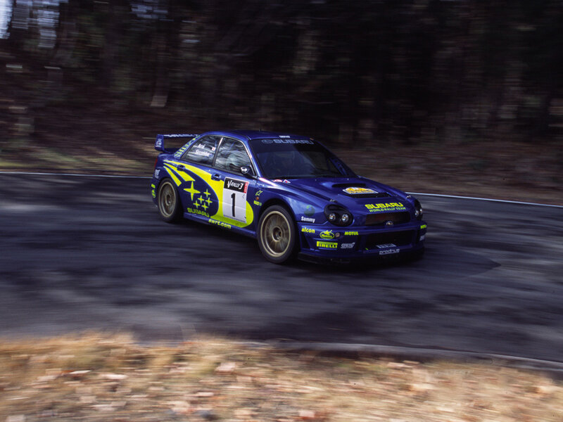blue rally car on a forest road