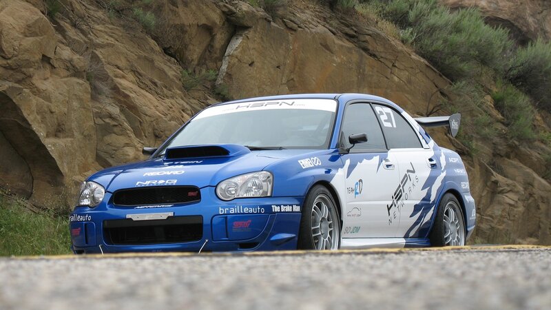 blue rally car on mountain road