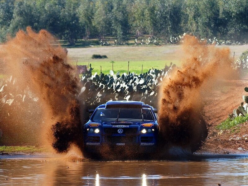 Blue rally car splashing mud