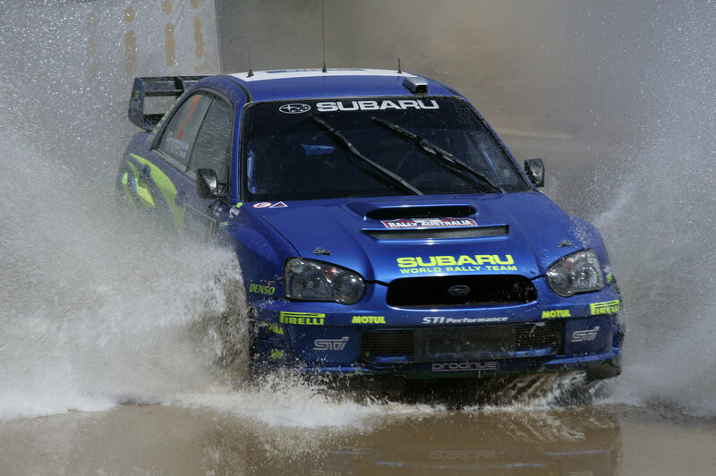 Blue rally car splashing through water