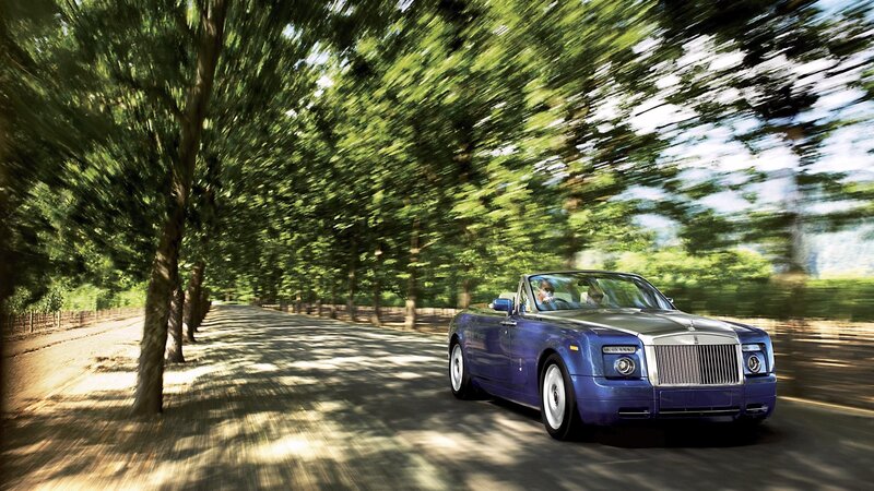 Blue Rolls-Royce convertible on a tree-lined road