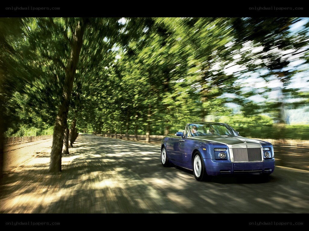 Blue Rolls-Royce convertible on a tree-lined road