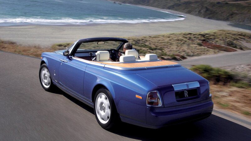 blue rolls-royce convertible on coastal road
