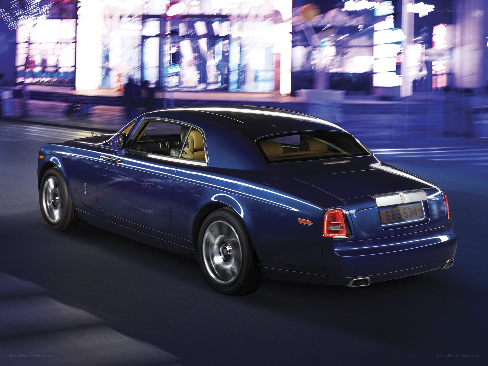 blue rolls-royce driving at night