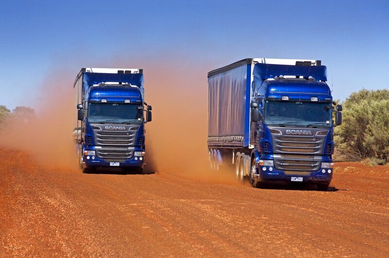 Blue Scania trucks on a dirt road