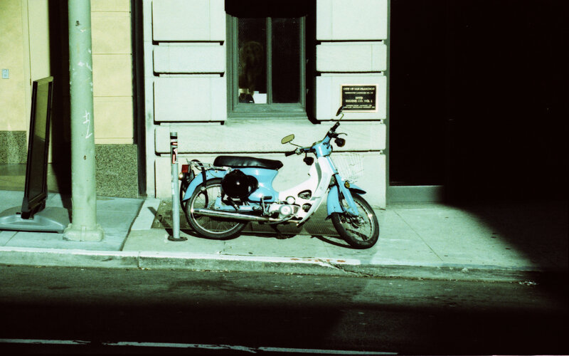 Blue scooter on sidewalk at night