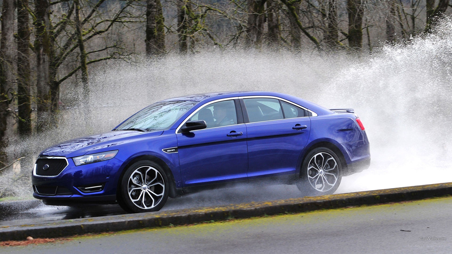 Blue sedan splashing through water