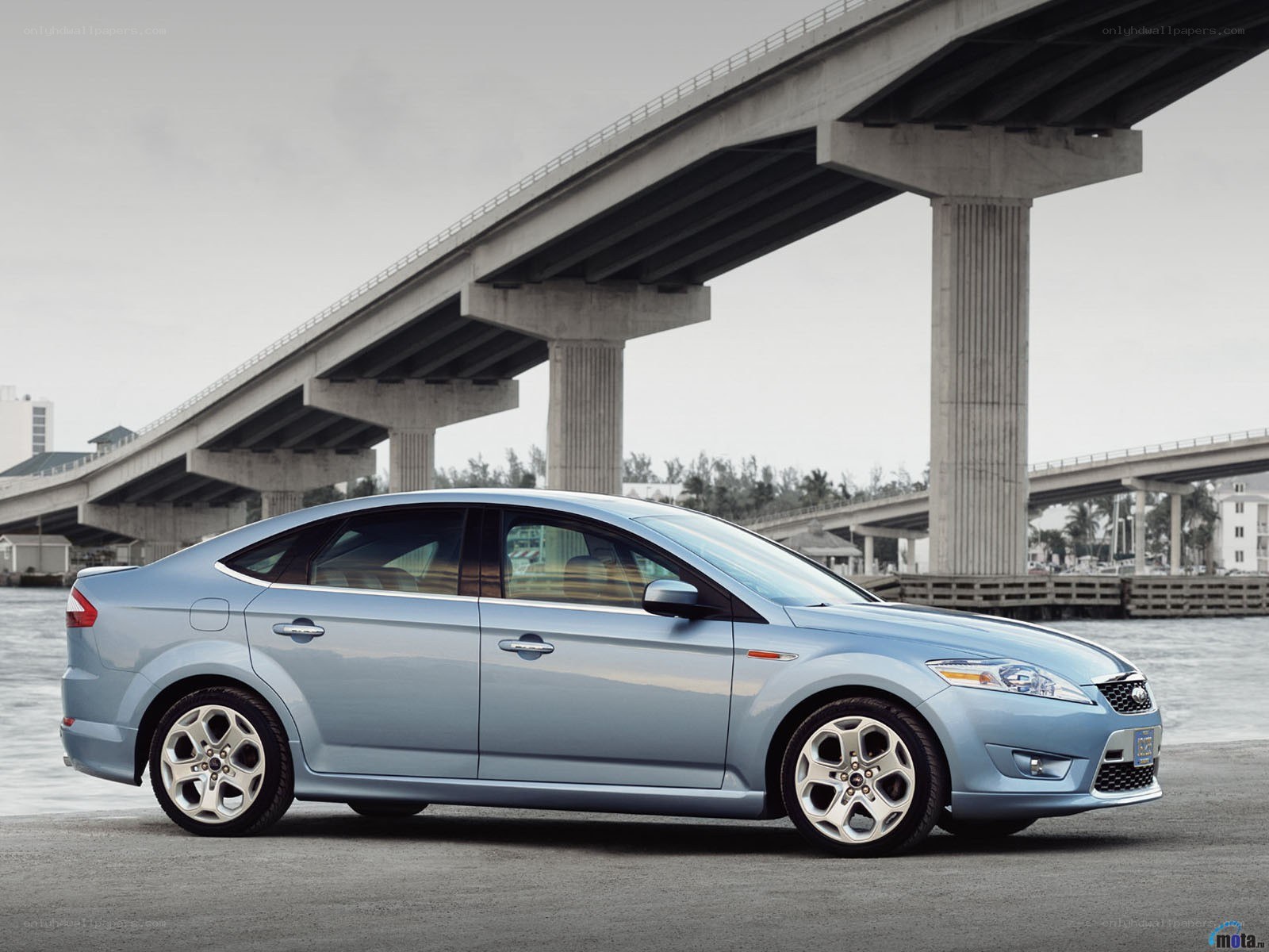 blue sedan under a bridge