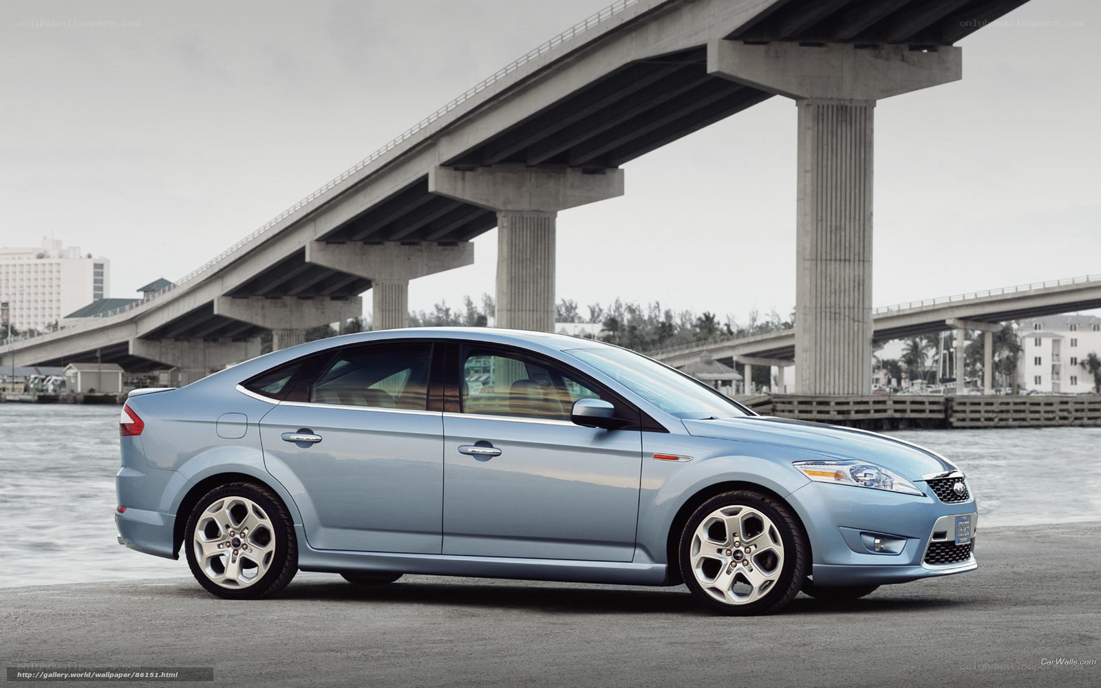 Blue sedan under a bridge