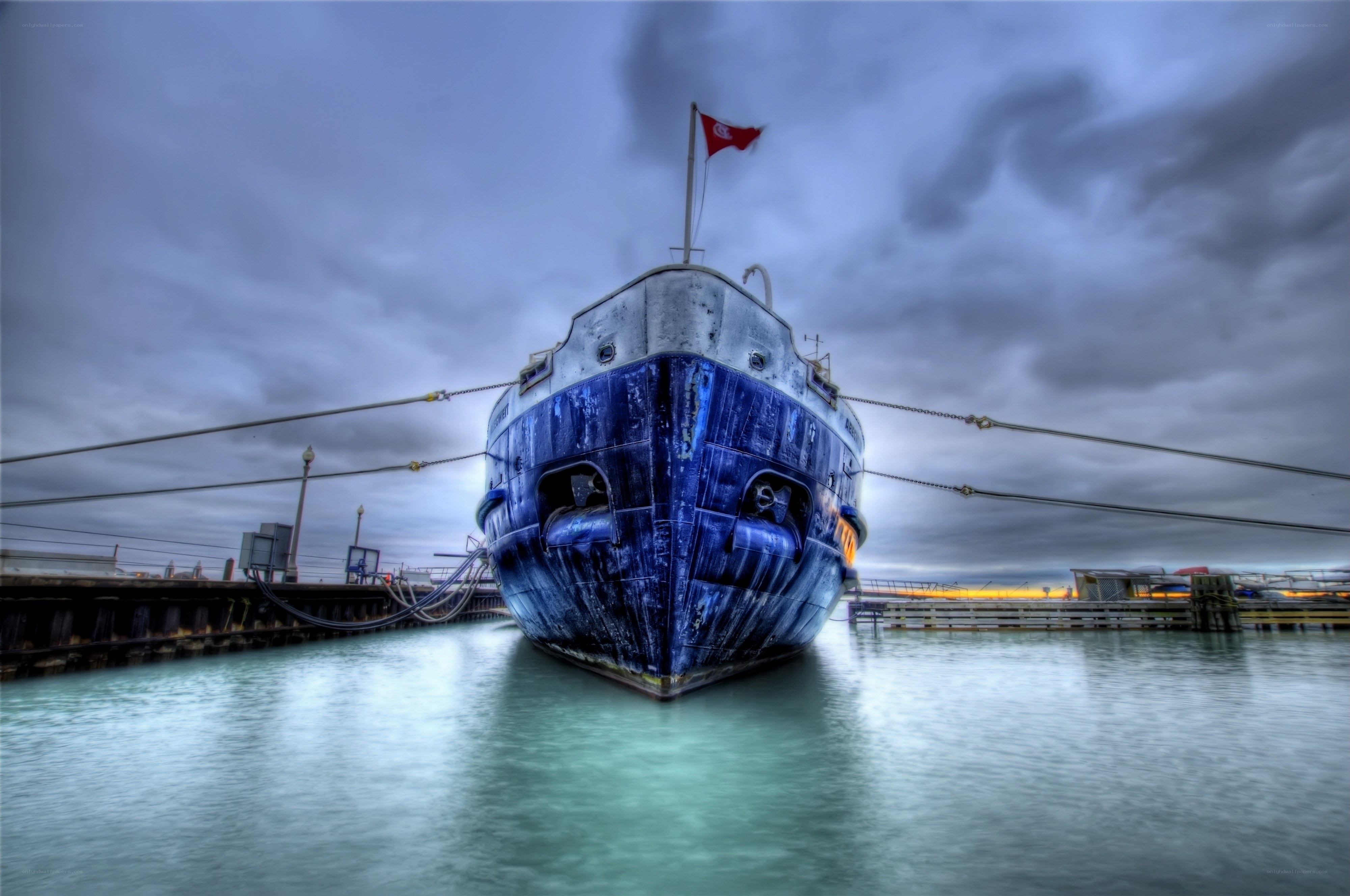 Blue ship at dock under cloudy sky