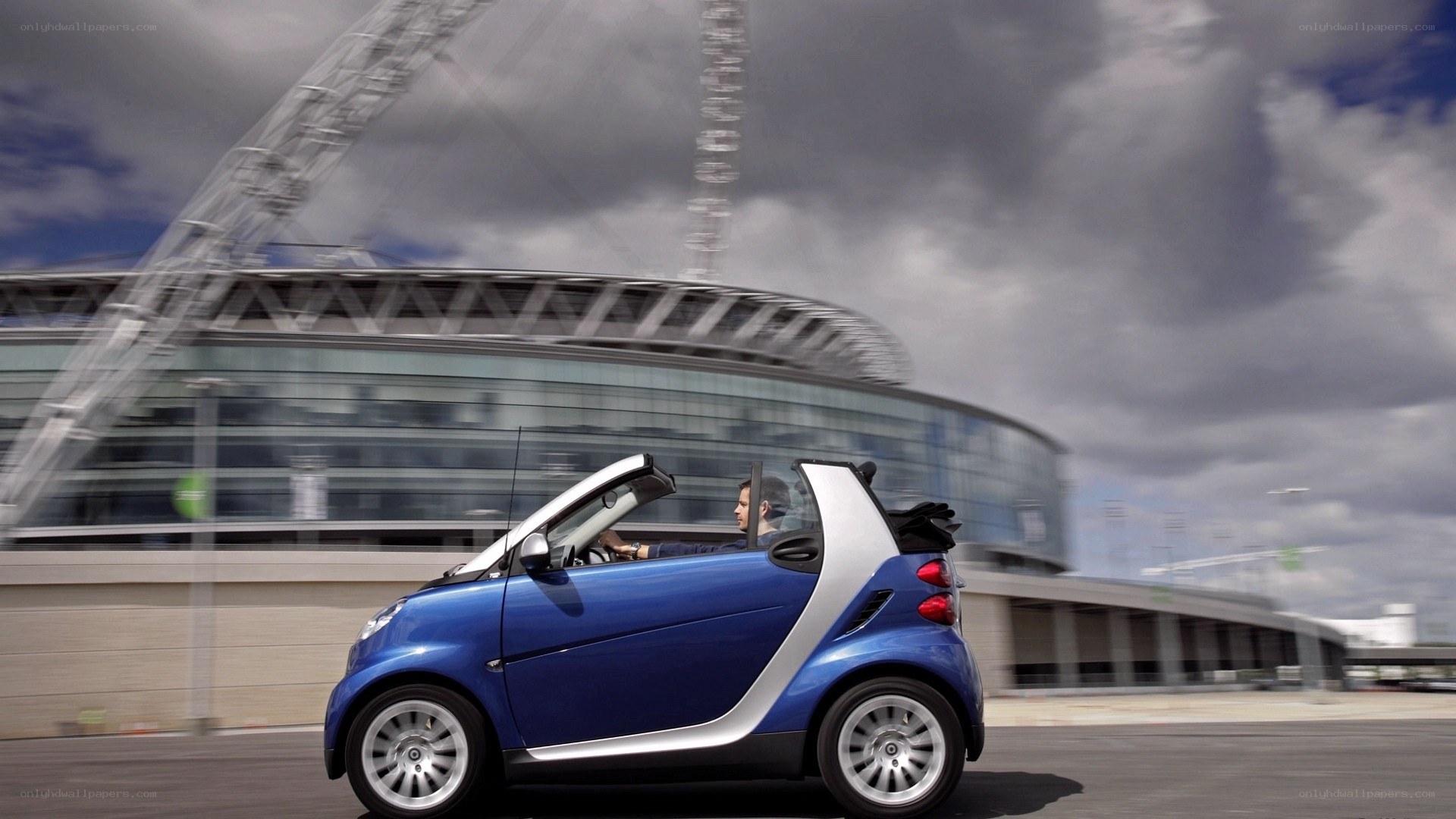 Blue smart car driving by stadium