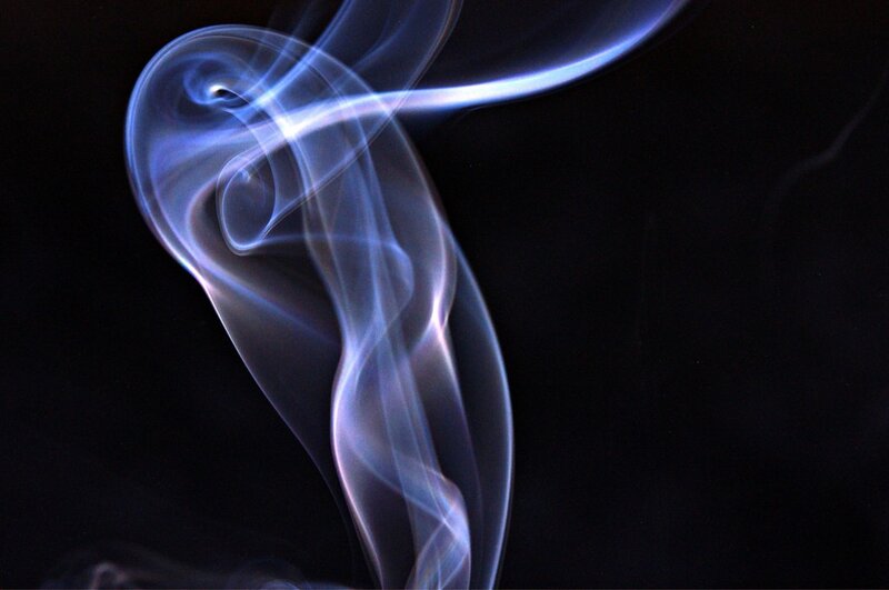 Blue smoke swirls in darkness