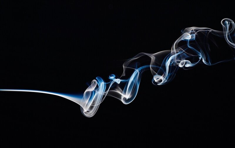 Blue smoke swirls on black
