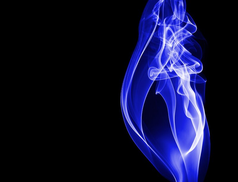 Blue smoke swirls on black