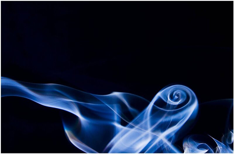 Blue smoke swirls on black