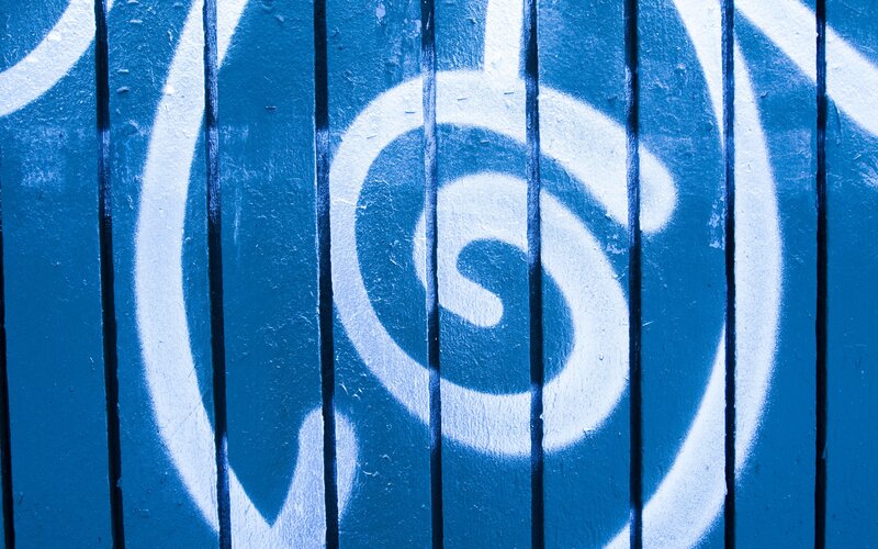 Blue spiral graffiti on wooden fence