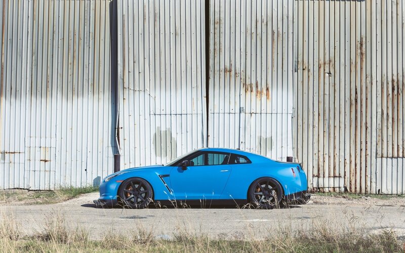 Blue sports car by a warehouse