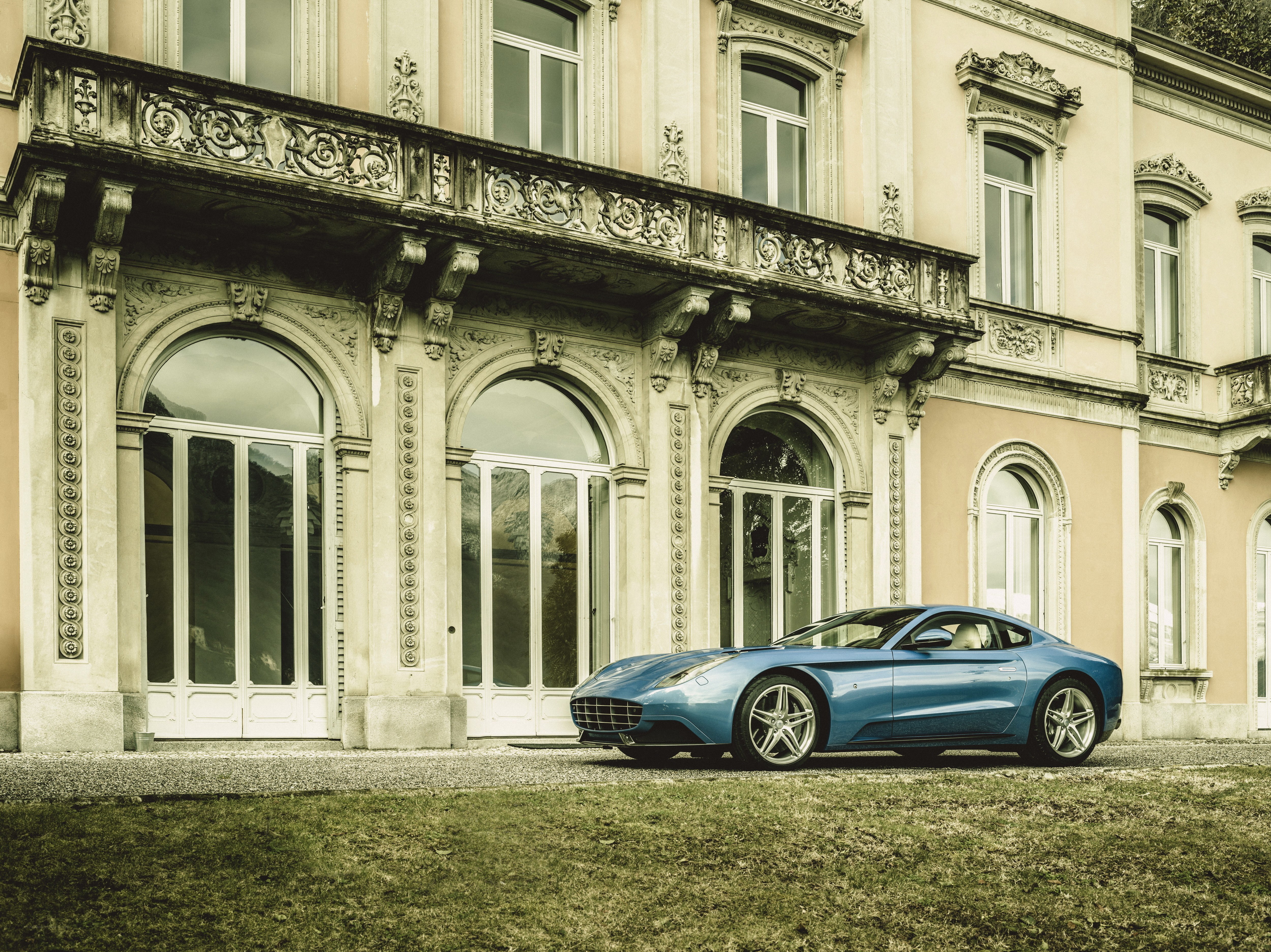 Blue sports car in front of mansion