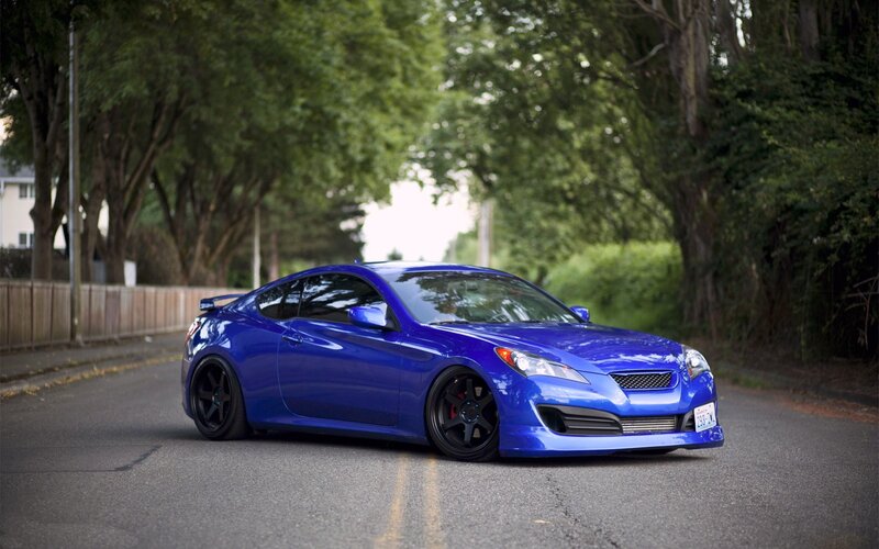 blue sports car on a tree-lined street