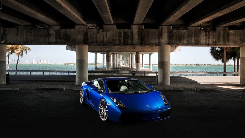 Blue sports car under a bridge