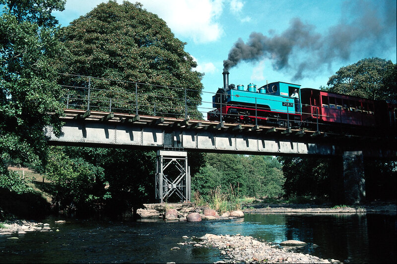 Blue steam train crossing bridge