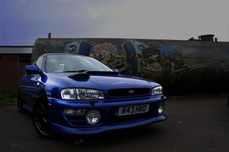 blue subaru in front of graffiti