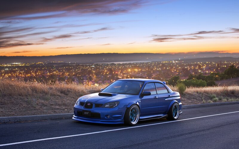 blue subaru on a hill at sunset