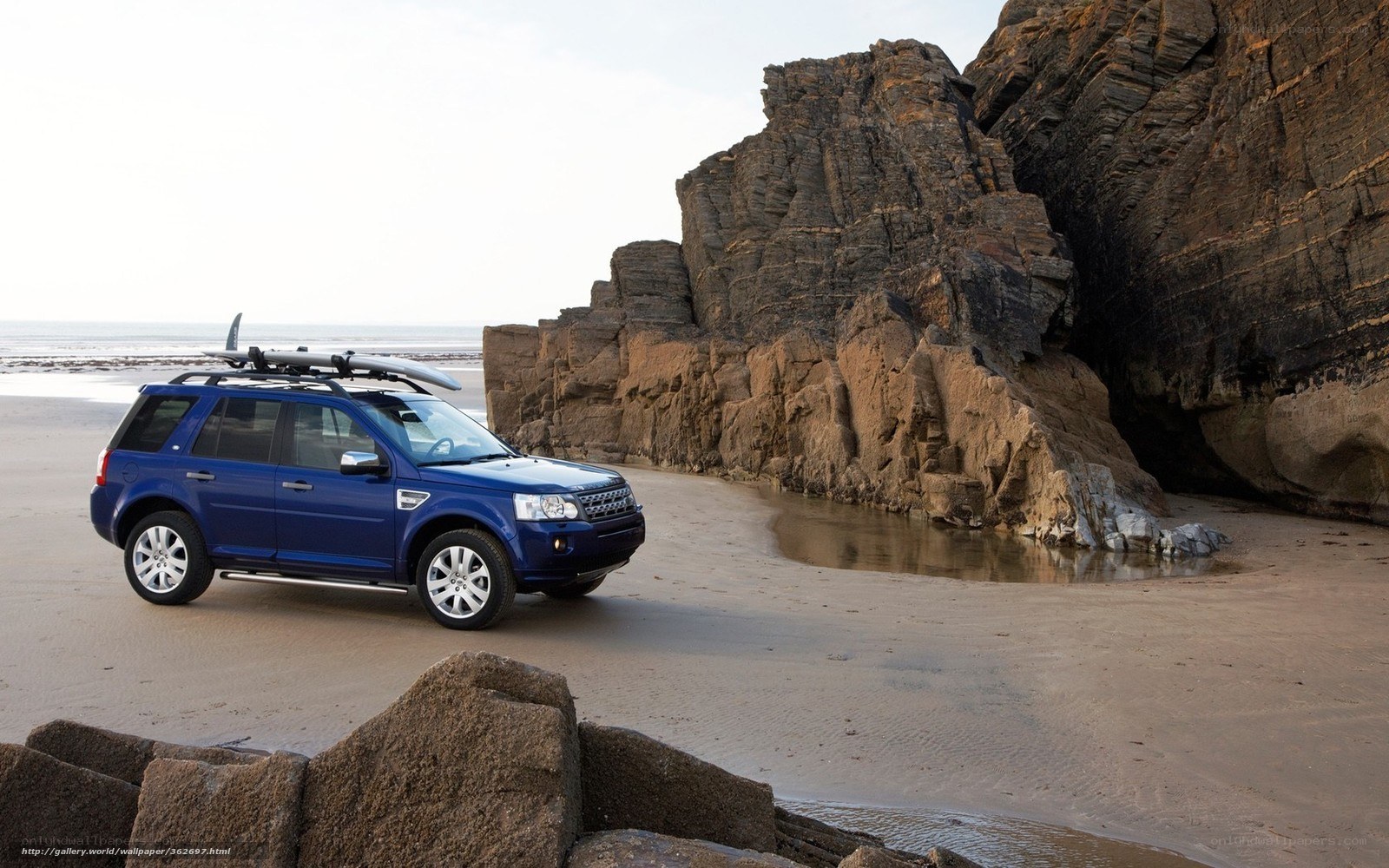 Blue SUV on a beach with surfboard