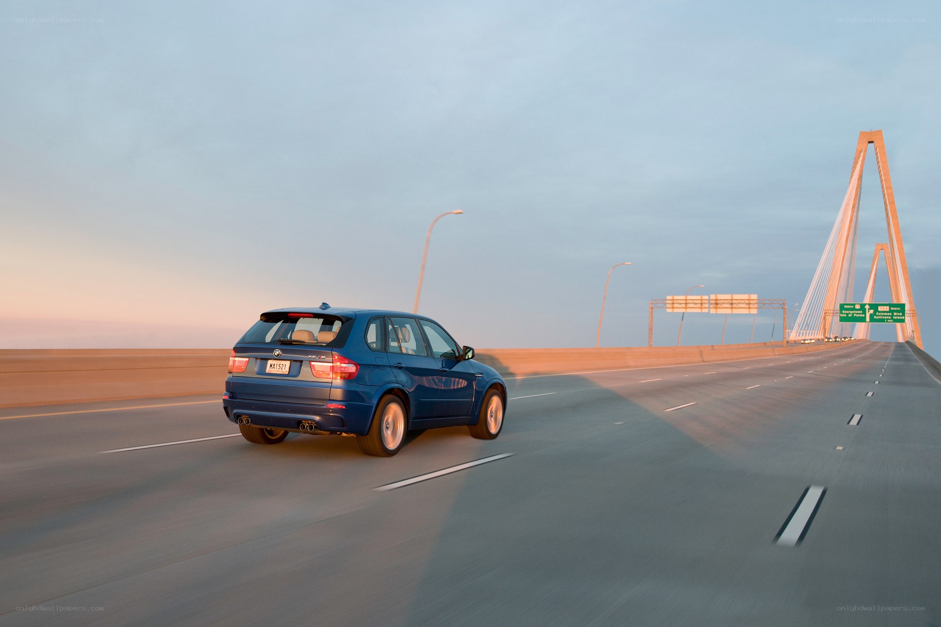 Blue SUV on a bridge at sunset
