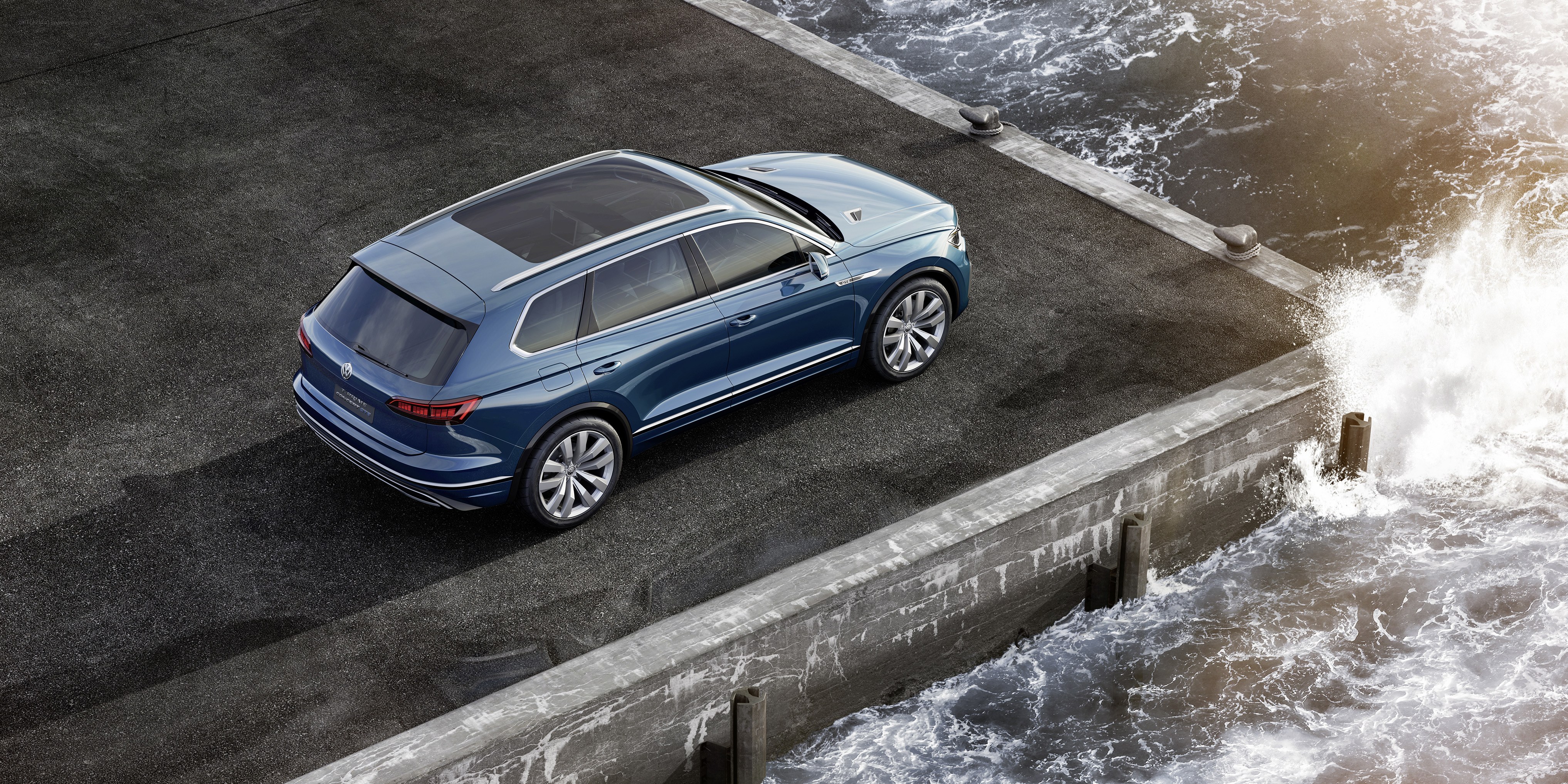 Blue SUV on pier by ocean