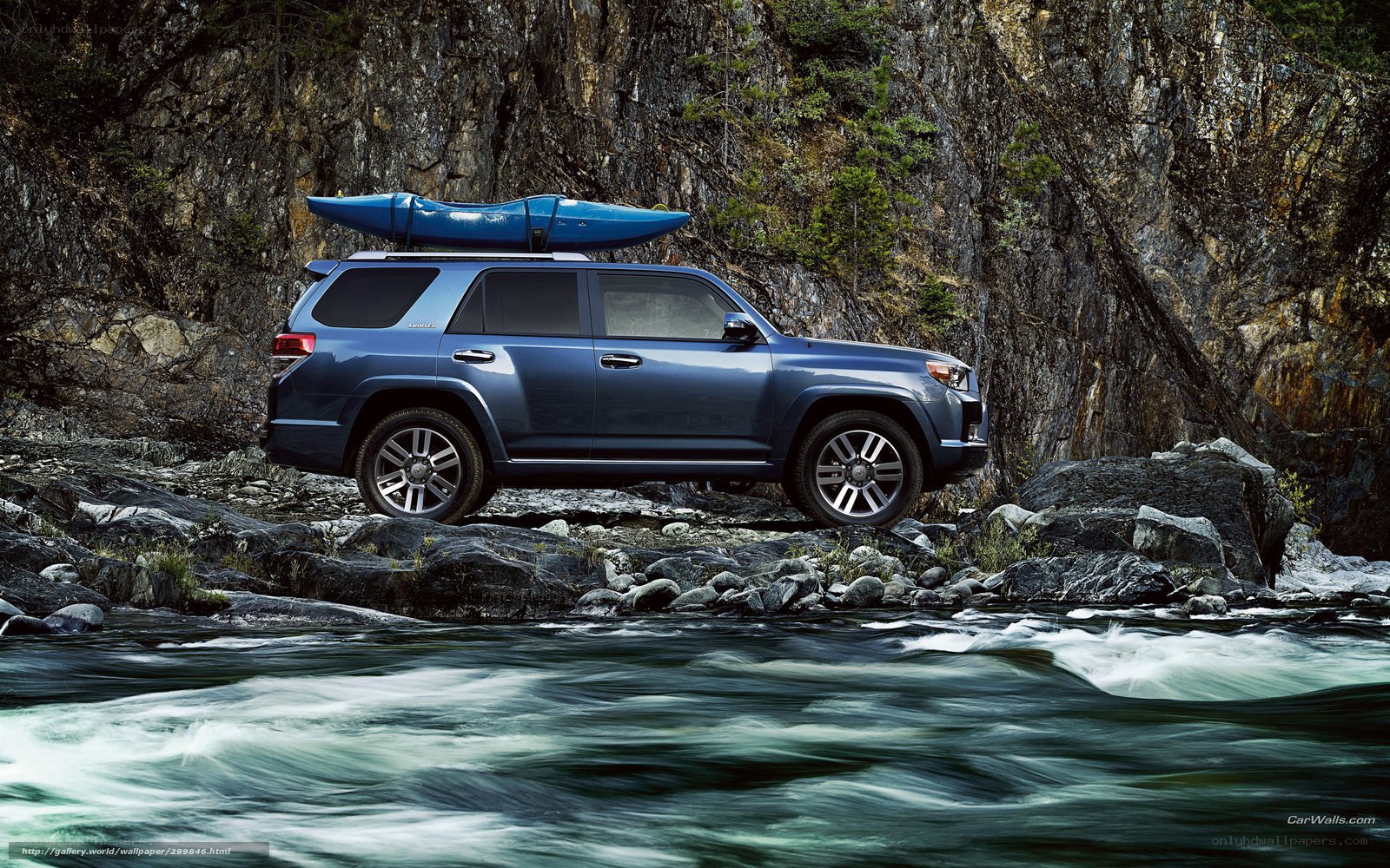 Blue SUV with kayak on riverbank