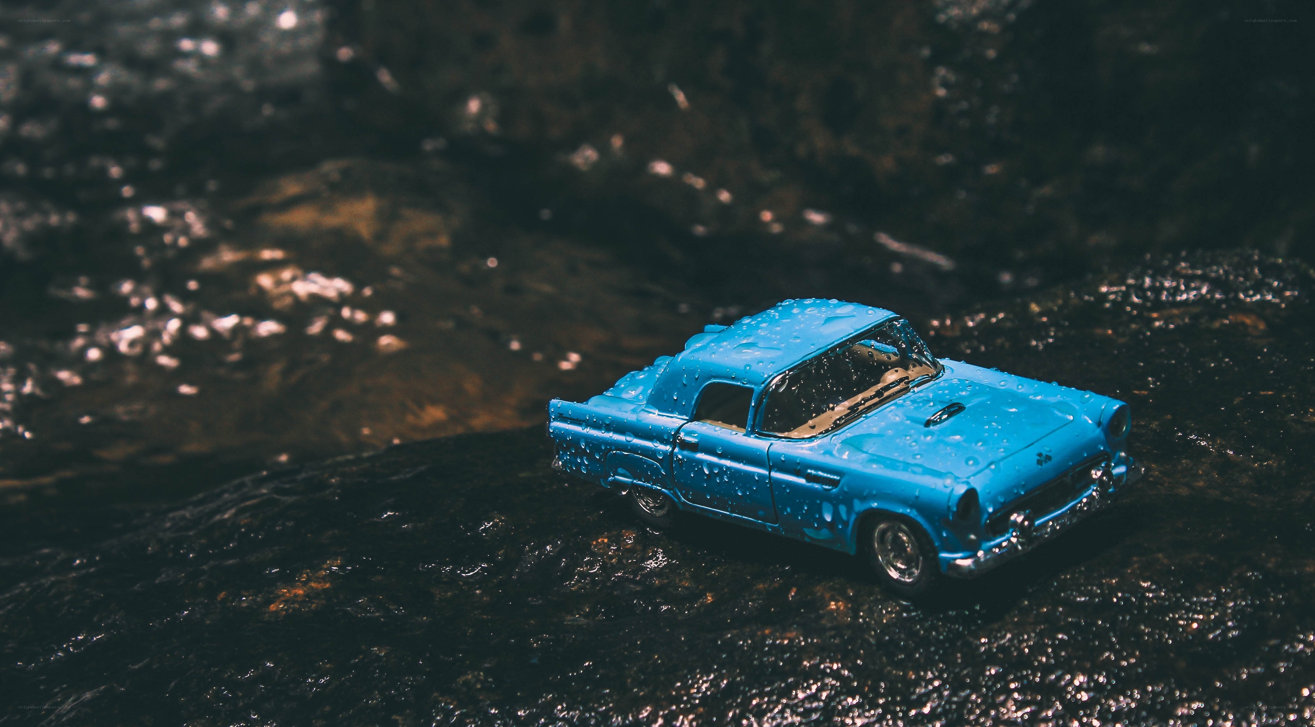 Blue toy car on wet rocks