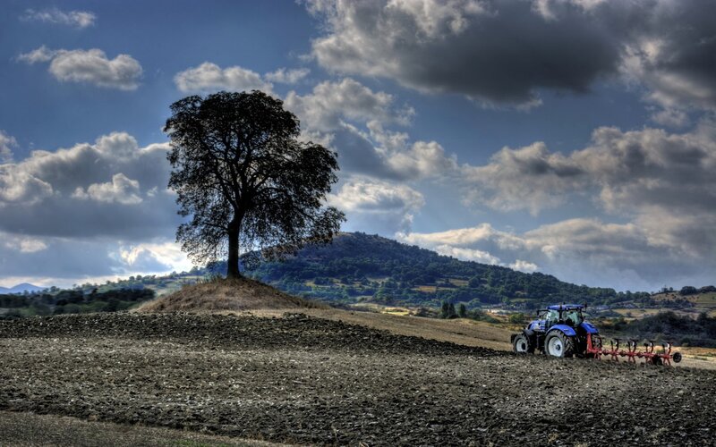 Blue Tractor Plowing Field — Dramatic